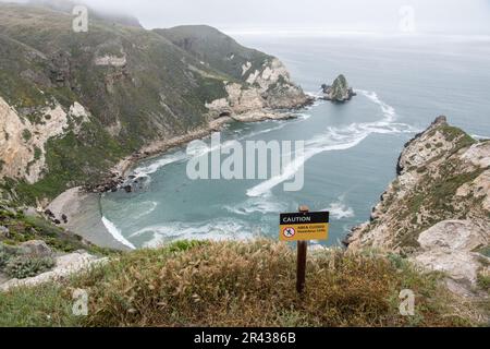 Ein Schild warnt Besucher vor gefährlichen Klippen und gefährlichen Wasserfällen am Potato Harbor Overlook im Channel Islands National Park, Kalifornien. Stockfoto