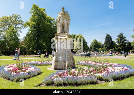 Eine Portland-Steinstatue von König Edward VII, die stolz auf einem Sockel inmitten wunderschöner Blumen im Beacon Park, Lichfield, steht. Stockfoto
