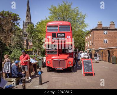 Gäste, die während des Lichfield Food Festivals in der British Bus Bar anstehen, einem umgebauten roten Doppeldeckerbus, um ein Getränk zu kaufen. Die Lichfield Kathedrale. Stockfoto