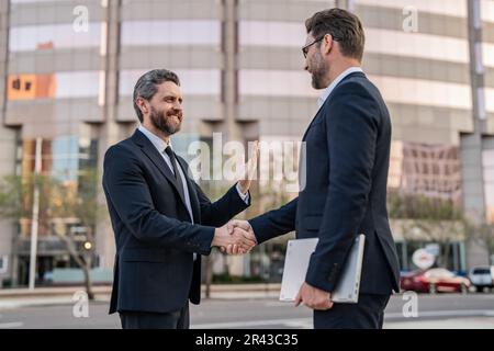Foto von zwei Geschäftsleuten, die sich die Hände schütteln. Zwei Geschäftsleute schütteln sich die Hand. Stockfoto
