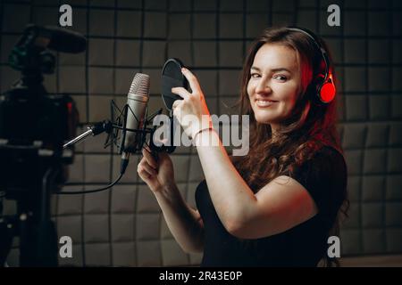 Eine attraktive Bloggerin spricht über professionelle Voice-Over- und Synchronisierungsfunktionen, nimmt Videos darüber für ihren Online-Vlog oder einige Tutorialkurse auf. Stockfoto