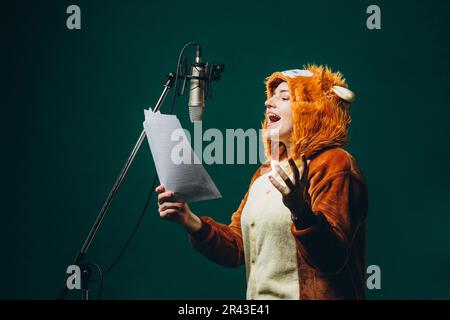 Die Frau bereitet sich und ein Material vor, bevor sie die Stimme aufnimmt. Schalldichter Raum für professionelle Stimmaufnahmen. Der Sprachkünstler arbeitet mit Material Befor Stockfoto