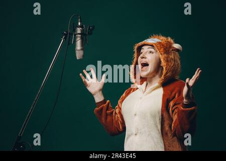 Die Frau bereitet sich und ein Material vor, bevor sie die Stimme aufnimmt. Schalldichter Raum für professionelle Stimmaufnahmen. Der Sprachkünstler arbeitet mit Material Befor Stockfoto