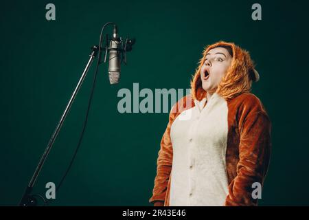 Die Frau bereitet sich und ein Material vor, bevor sie die Stimme aufnimmt. Schalldichter Raum für professionelle Stimmaufnahmen. Der Sprachkünstler arbeitet mit Material Befor Stockfoto