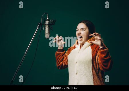 Die Frau bereitet sich und ein Material vor, bevor sie die Stimme aufnimmt. Schalldichter Raum für professionelle Stimmaufnahmen. Der Sprachkünstler arbeitet mit Material Befor Stockfoto