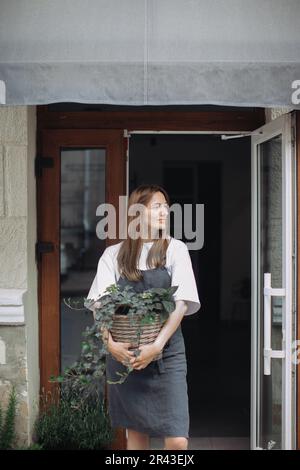 Blumenmädchen mit Efeu in der Nähe eines Blumenladens. Stockfoto