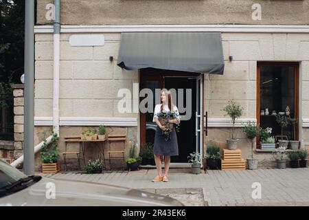 Blumenmädchen mit Efeu in der Nähe eines Blumenladens. Stockfoto