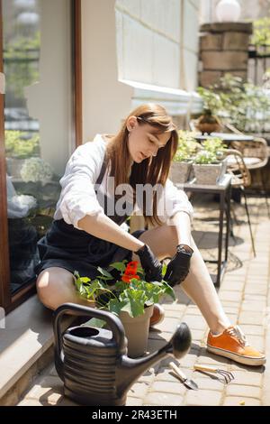 Eine Gärtnerin pflanzt Blumen in einen Topf – ein Stockfoto Stockfoto