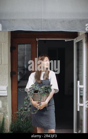 Blumenmädchen mit Efeu in der Nähe eines Blumenladens. Stockfoto