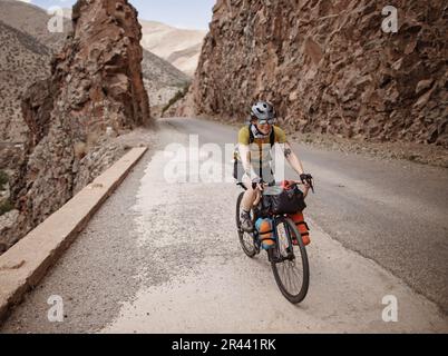 Eine Radfahrerin fährt auf einer Bergstraße im Atlasgebirge Stockfoto