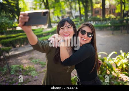 Zwei junge lateinische Freundinnen, die im Wald spazieren gehen Stockfoto