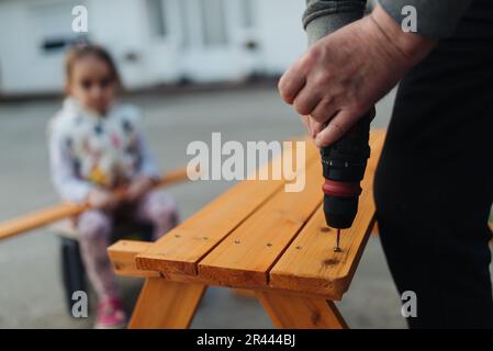 Ein alter Mann, der Elektrobohrer benutzt und mit seiner Enkelin arbeitet Stockfoto