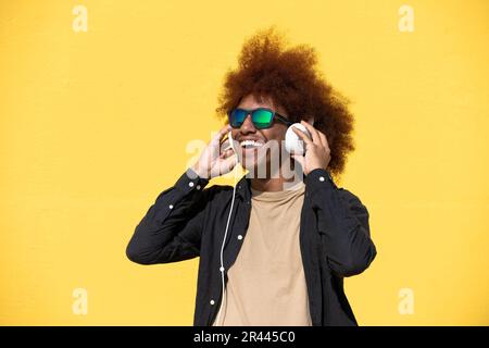 Fröhlicher junger Mann mit Sonnenbrille und Kopfhörern, der Spaß hat Stockfoto