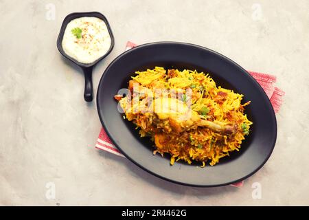 Hühnchen Biryani/murg Pulao. Garniert mit gebratenen Zwiebeln und gehacktem Koriander. Biryani serviert mit Rita ist ein berühmtes würziges nicht-vegetarisches Gericht Indiens. Stockfoto