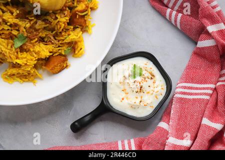 Hühnchen Biryani/murg Pulao. Garniert mit gebratenen Zwiebeln und gehacktem Koriander. Biryani serviert mit Rita ist ein berühmtes würziges nicht-vegetarisches Gericht Indiens. Stockfoto