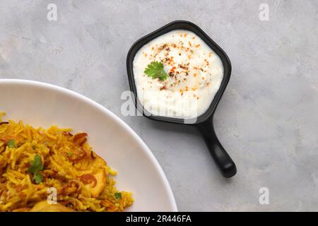 Hühnchen Biryani/murg Pulao. Garniert mit gebratenen Zwiebeln und gehacktem Koriander. Biryani serviert mit Rita ist ein berühmtes würziges nicht-vegetarisches Gericht Indiens. Stockfoto