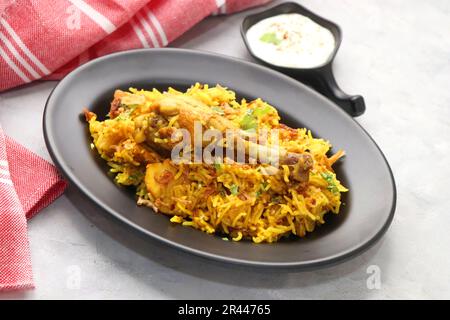 Hühnchen Biryani/murg Pulao. Garniert mit gebratenen Zwiebeln und gehacktem Koriander. Biryani serviert mit Rita ist ein berühmtes würziges nicht-vegetarisches Gericht Indiens. Stockfoto