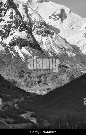 Blick zwischen den Bergen in Norwegen, durch die eine Straße in schwarzem Weiß führt. Schnee in den Bergen. Landschaftsaufnahmen aus dem Norden in Skandinavien Stockfoto