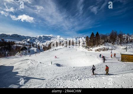 Bohinj, Slowenien - Vogel Ski Resort in Bohinj in den Julischen Alpen an einem sonnigen Wintertag mit Skipisten, Skifahrern, Snowboardern und blauem Himmel und Wolken Stockfoto