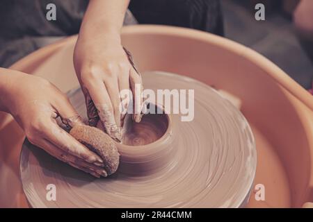 Eine Nahaufnahme-Frau arbeitet Handwerk auf Töpferrad und macht Tontopf Terrakotta. Stockfoto