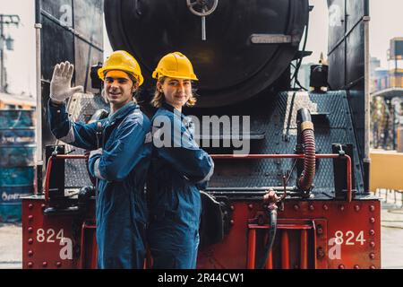 Zugingenieur-Team arbeitet Service Wartung alte schmutzige klassische Dampflokomotive in der Bahnhofswerkstatt. Stockfoto