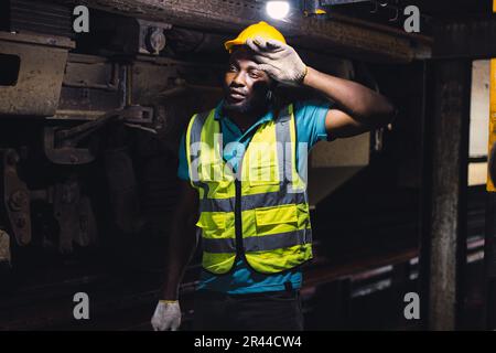 Müde, erschöpfter Arbeiter, harte Arbeit, die Mechaniker von Lokomotiven fühlen sich ermüdet Arbeit in der Bahnwerkstatt Service Station schmutzige, heiße Arbeitsplatzmaschine Stockfoto