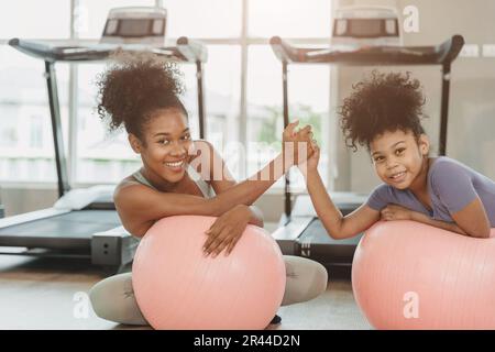 Fröhliche sportliche Fitness gesunde Frau mit lächelndem Kind im Laufband des Sportclubs Stockfoto