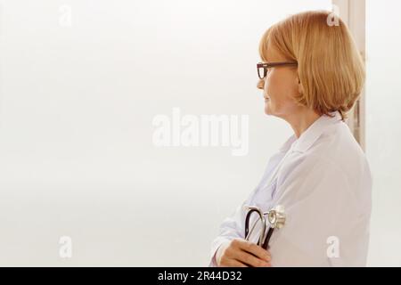 Der Stress des Arztes. Leitendes medizinisches Personal weiblich mit Stethoskop, das auf ernsthafte Sorgen denkt. Stockfoto
