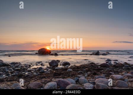 Sonnenuntergang am Ostseestrand voller Felsen in Vidzeme, Lettland. Langzeitbelichtung. Stockfoto