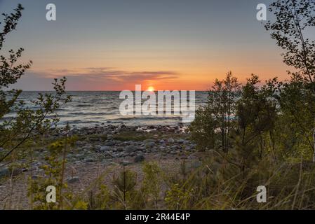 Sonnenuntergang am Ostseestrand voller Felsen in Vidzeme, Lettland. Stockfoto