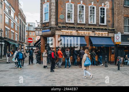 London, Vereinigtes Königreich - 13. April 2023: Besucher gehen am Blue Posts Pub in Soho vorbei, einer Gegend Londons, die für LGBTQ+ Bars, Restaurants und Clubs berühmt ist. Stockfoto