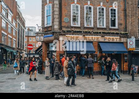 London, Vereinigtes Königreich - 13. April 2023: Besucher gehen am Blue Posts Pub in Soho vorbei, einer Gegend Londons, die für LGBTQ+ Bars, Restaurants und Clubs berühmt ist. Stockfoto