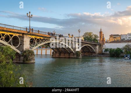 Triana-Brücke (Puente de Triana) und Schloss San Jorge (Castillo de San Jorge) am Fluss Guadalquivir bei Sonnenuntergang - Sevilla, Andalusien, Spanien Stockfoto