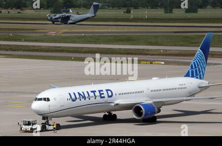 Brandenburg, Deutschland. 26. Mai 2023 Eine Boeing 767-424(er) der US-Fluggesellschaft United Airlines wird auf dem Vorfeld für den United-Jungfernflug von Berlin nach Washington, DC, am Flughafen Berlin Brandenburg Willy Brandt auf das Vorfeld gezogen. Im Hintergrund landet ein Airbus A400M der deutschen Luftwaffe. Foto: Wolfgang Kumm/dpa/Alamy Live News Stockfoto