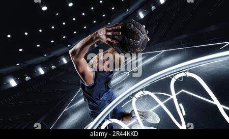 Dynamisches Bild eines jungen Mannes, Basketballspieler in Bewegung, der Ball im Sprung in den Korb auf dem 3D Basketballfeld wirft. Siegerziel Stockfoto