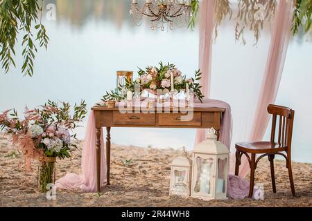 Wunderschöne Hochzeitsdekoration. Hochzeit am Strand, Roses Retro-Stil. Hochzeitsfloristik Dekoration Stockfoto