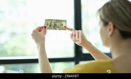 Eine Frau, die Wasserzeichen auf Geld-Dollar vor der Fensterschließung studiert Stockfoto