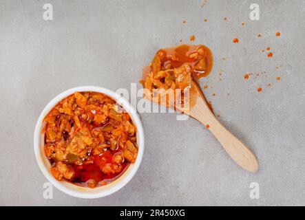 Traditionelles südafrikanisches Mango Atchar oder Achar auf meliertem Grau mit Schaufel Stockfoto