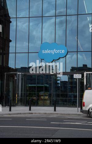 Ein weißer Lieferwagen, der vor einem modernen Geschäftsgebäude mit einem markanten Salesforce Logo geparkt ist Stockfoto