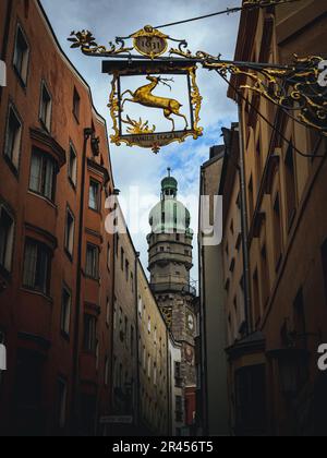 Urbane Szene in der mittelalterlichen Altstadt von Innsbruck in einer engen Gasse mit Kirchturm und Herrenschild Stockfoto