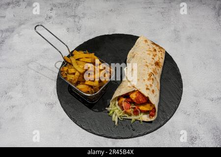 Indische Dishe kulinarisches Still Life. Tandoori Wrap serviert mit Pommes Frites auf einem Teller Stockfoto