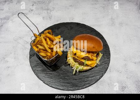 Indische Dishe kulinarisches Still Life. Doppeltes Käse-Rindfleisch mit Pommes Frites auf einem Teller Stockfoto