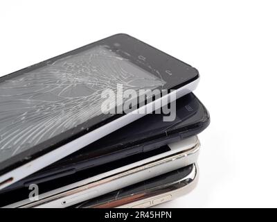 Beschädigte Mobiltelefone. Ein Haufen kaputter Smartphones. Benutzte Telefone mit hellem Hintergrund. Stockfoto