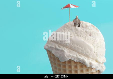 Ein kleiner Geschäftsmann liest am Eisstrand mit Sonnenschirm Zeitung Stockfoto