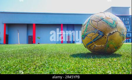 Nahaufnahme eines klassischen Fußballballs, der an einem sonnigen Tag auf dem Rasen liegt Stockfoto