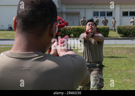 Airman 1. Class Keanu Camacho, 18. Security Forces Squadron Defender, fordert Airman 1. Class Dalon Alford, 18. SFS Defender heraus, nachdem er auf dem Luftwaffenstützpunkt Kadena, Japan, am 6. März 2023 mit Oleoresin-Capiscum-Spray besprüht wurde. Der Kurs bestand darin, gesprüht zu werden, eine Reihe von verschiedenen Stabschlägen gegen mehrere Angreifer zu durchlaufen und dann schließlich eine Person zu entschärfen und sie mit Handschellen zu versehen, bevor sie das Spray abspülte. Stockfoto