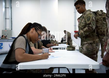 USA Air Force Staff Sgt. MEIKO Cantrell, 380. Expeditionary Logistics Readiness Squadron Passenger Travel Journeyman, prüft die Unterlagen eines US-Soldaten, der dem 4. Bataillon 3. Air Defense Artillery Regiment zugeteilt wurde, die durch eine Umschublinie am Al Dhafra Air Base, Vereinigte Arabische Emirate, am 30. Januar 2023 ausgeliefert wurden. Durch die Neubereitstellung wird sichergestellt, dass die Servicemitarbeiter ordnungsgemäß von ihrem Bereitstellungsort entfernt werden und mit minimalen Verzögerungen zu ihren Heimatstationen zurückkehren. Stockfoto