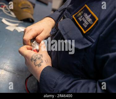 Electrician's Mate 2. Class Aaron Iverson, aus Chicago, der ersten Flugzeugträger der Klasse USS Gerald R. FordÕs (CVN 78), technische Abteilung, inspiziert persönliche elektronische Geräte für die Verwendung an Bord, 1. April 2023. Ford führt im Atlantik Routineeinsätze und Schulungen durch, um die Einsatzbereitschaft aufrechtzuerhalten. Als erstklassiges Schiff von Ford-Flugzeugträgern stellt CVN 78 einen Generationssprung in den USA dar NavyÕs Fähigkeit, Energie auf globaler Ebene zu projizieren. Stockfoto