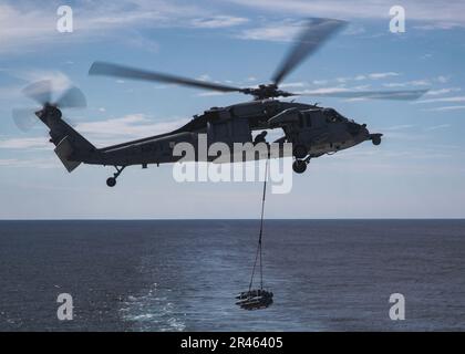 Ein MH-60s Knighthawk, angeschlossen an die "Tridents" des Helicopter Sea Combat Squadron (HSC) 9, transportiert Munition während einer Ladung mit USNS Medgar Evers (T-AKE 13), 31. März 2023. Ford führt im Atlantik Routineeinsätze und Schulungen durch, um die Einsatzbereitschaft aufrechtzuerhalten. Als erstklassiges Schiff von Ford-Flugzeugträgern stellt CVN 78 einen Generationssprung in den USA dar Die Fähigkeit der Navy, Energie auf globaler Ebene zu projizieren. Stockfoto