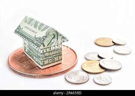 Amerikanischer Dollar in Hausform mit Münzen auf weißem Hintergrund Stockfoto